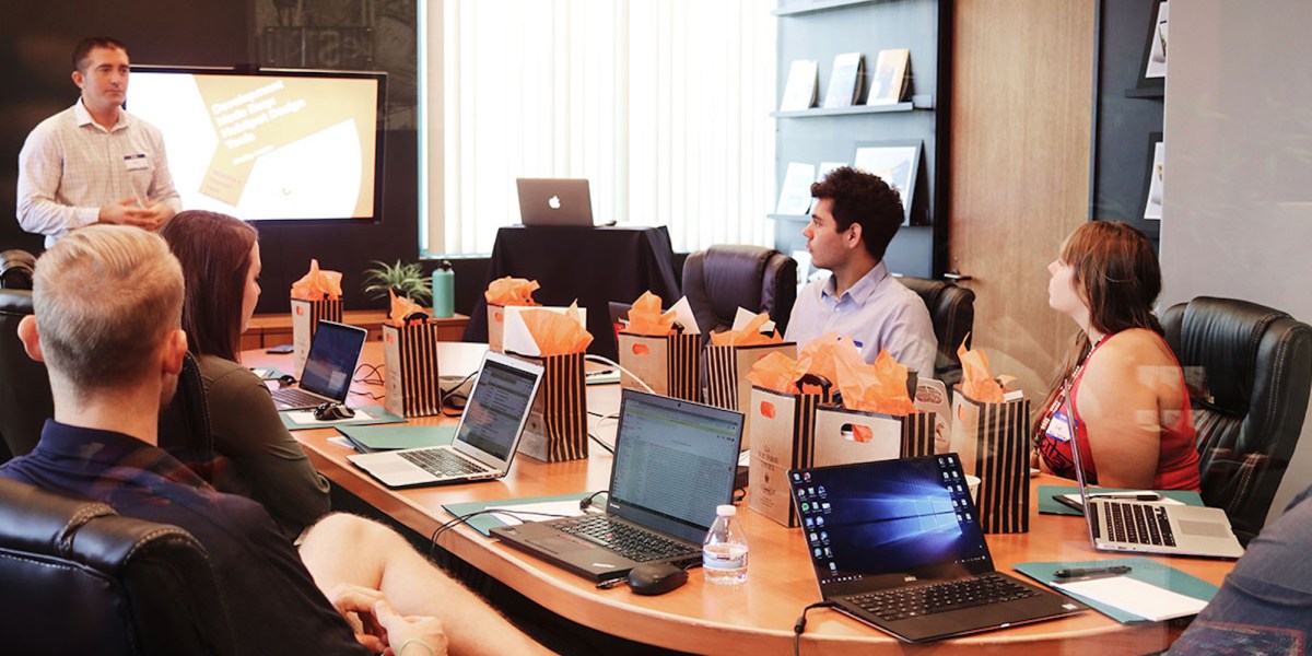 a group of people sitting at a table using a laptop computer