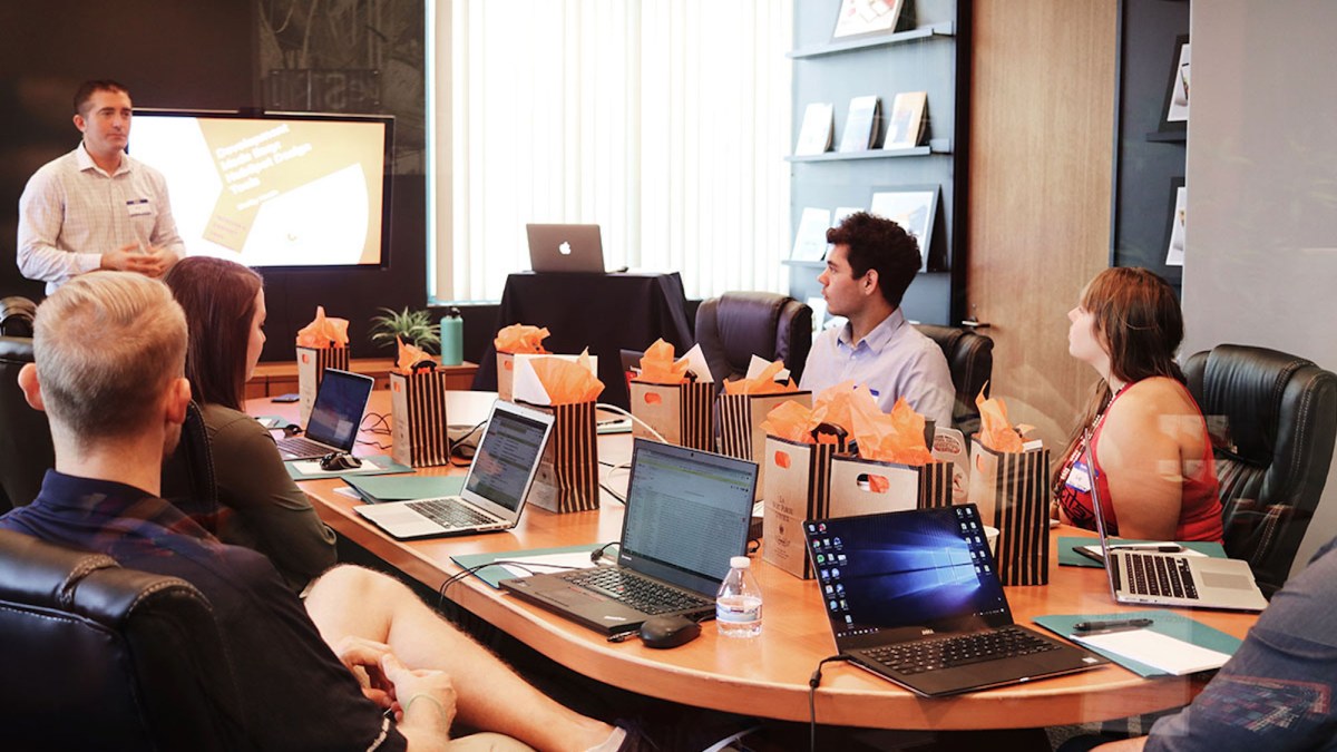 a group of people sitting at a table using a laptop computer