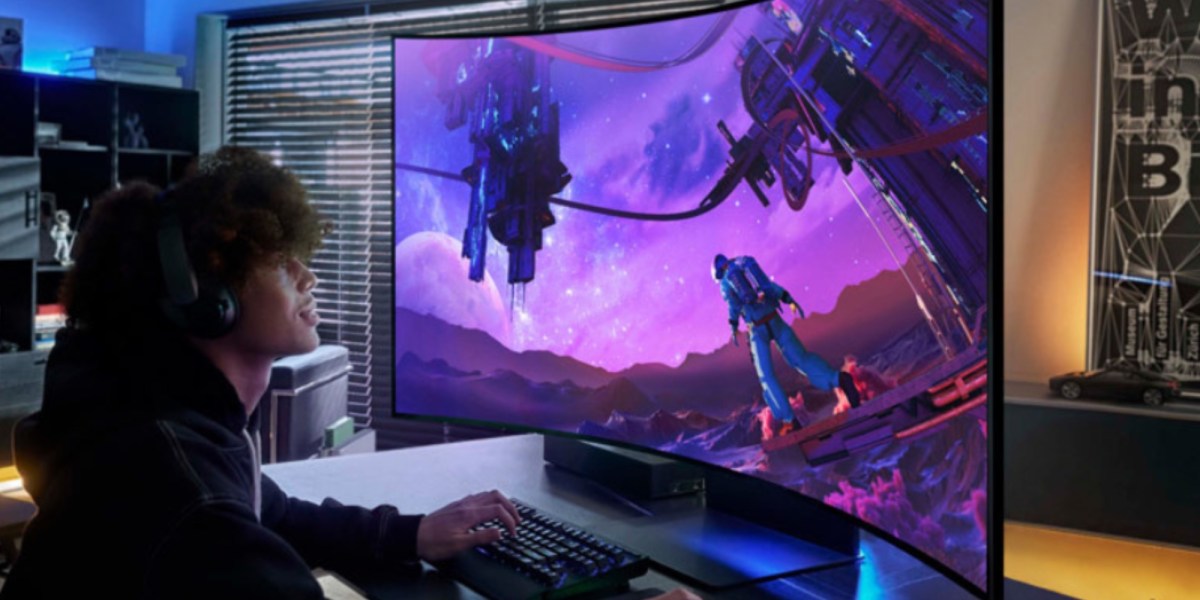 a man sitting at a desk with a laptop computer monitor and keyboard