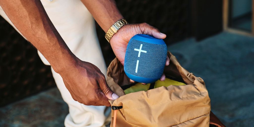 A person putting the Wonderboom 4 bluetooth speaker inside a backpack.