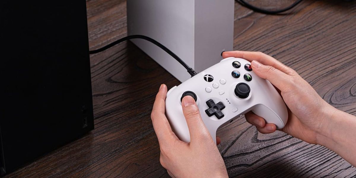 Image showing a person holding 8BitDo's Ultimate wired controller in white.