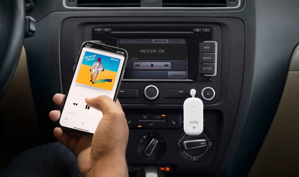 A person holding a phone in front of a car