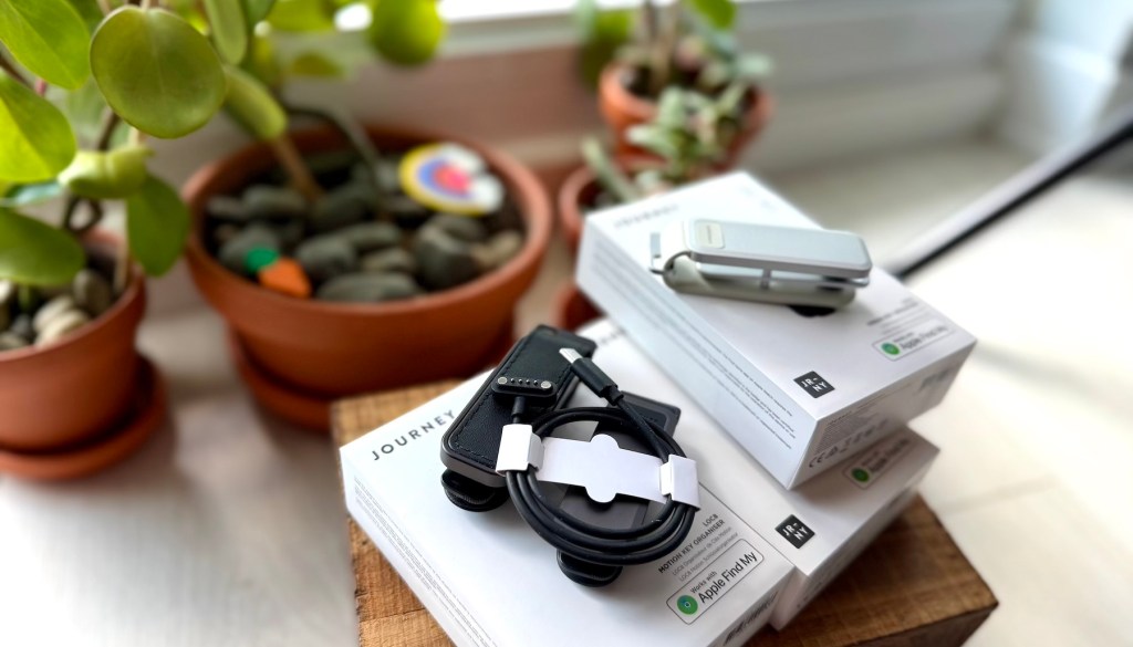 A stack of boxes with a phone charger and a smart watch