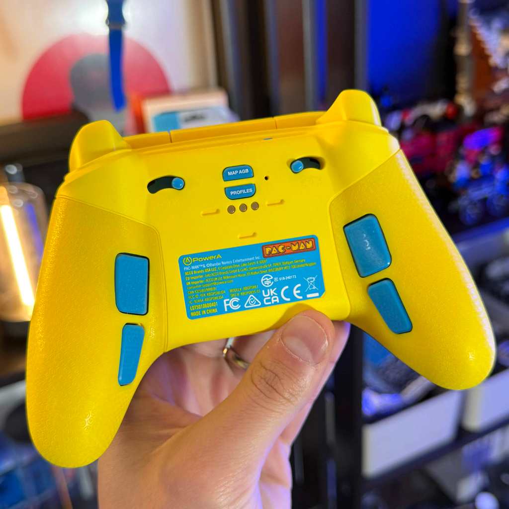 A hand holding a yellow video game controller