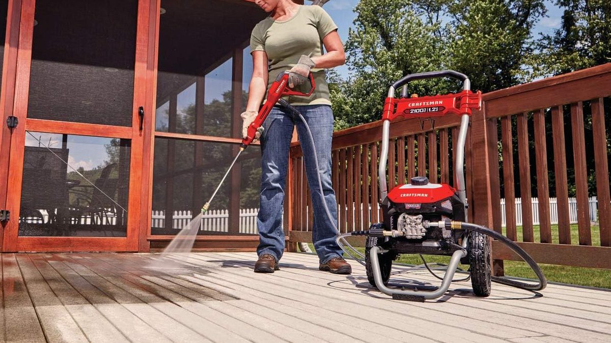 A woman spraying a deck with a power washer