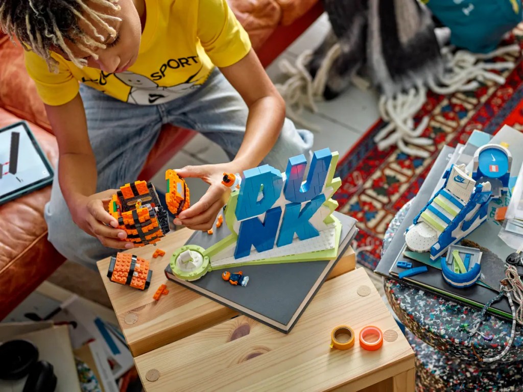 A person sitting on a table with LEGO Nike Dunk set