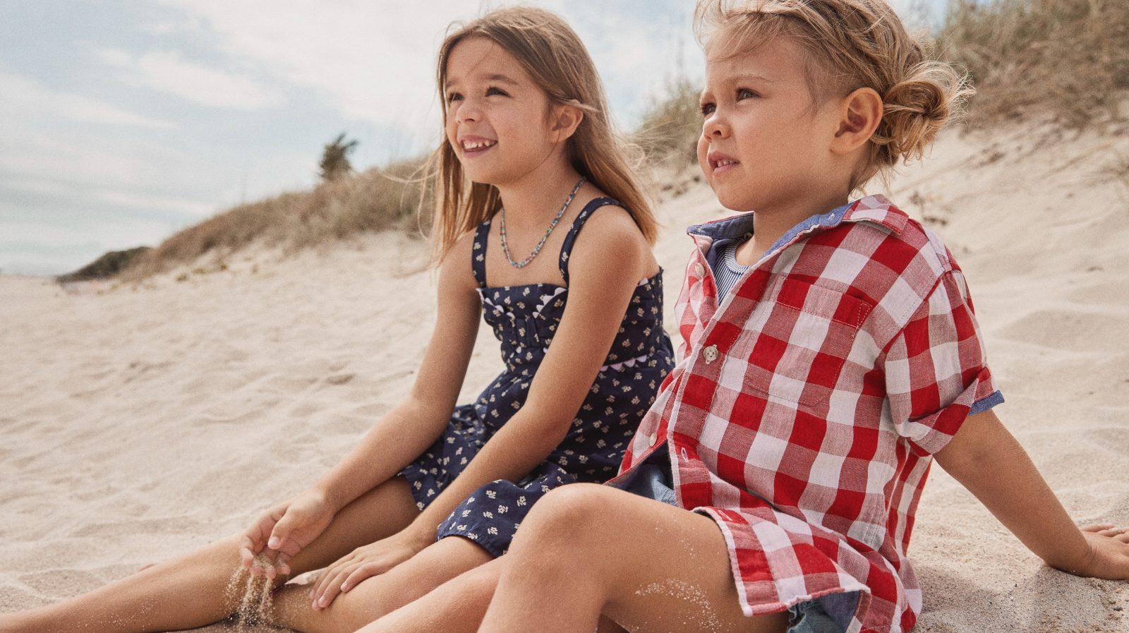 A boy and girl sitting on sand