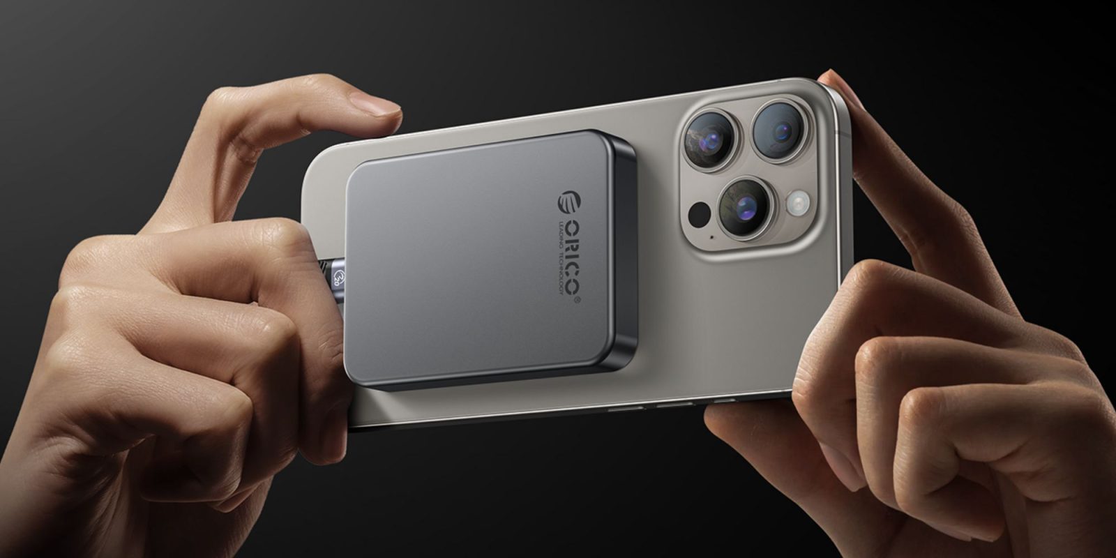 Image showing a person using an iPhone with a MagSafe SSD attached to it.