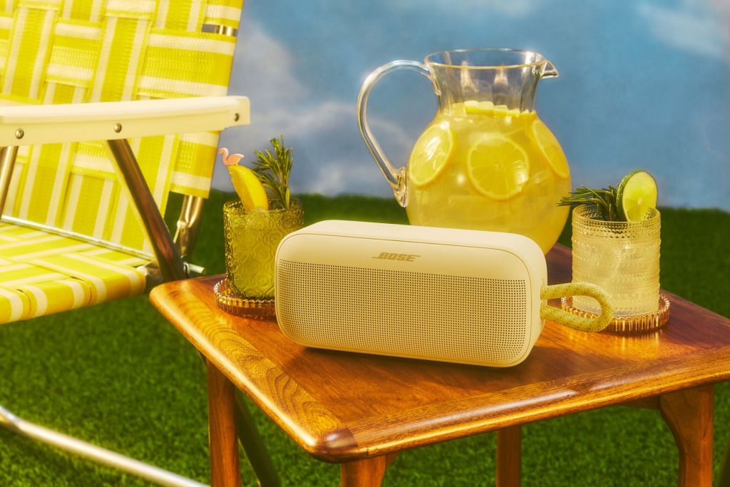 A white speaker on a table with a pitcher of lemonade and a chair