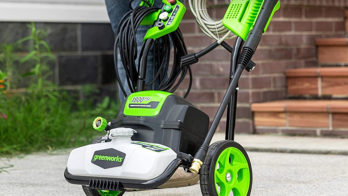 A person standing next to a green and black lawnmower