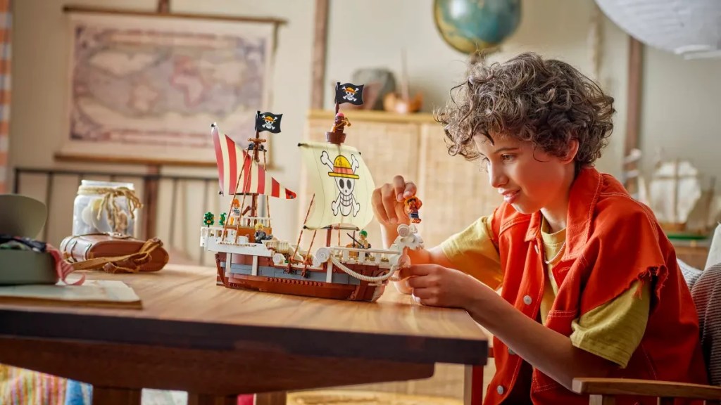 A boy playing with the LEGO Going Merry Pirate Ship set