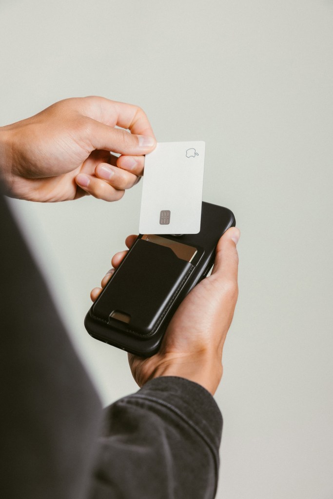 A person holding a credit card and a credit card reader