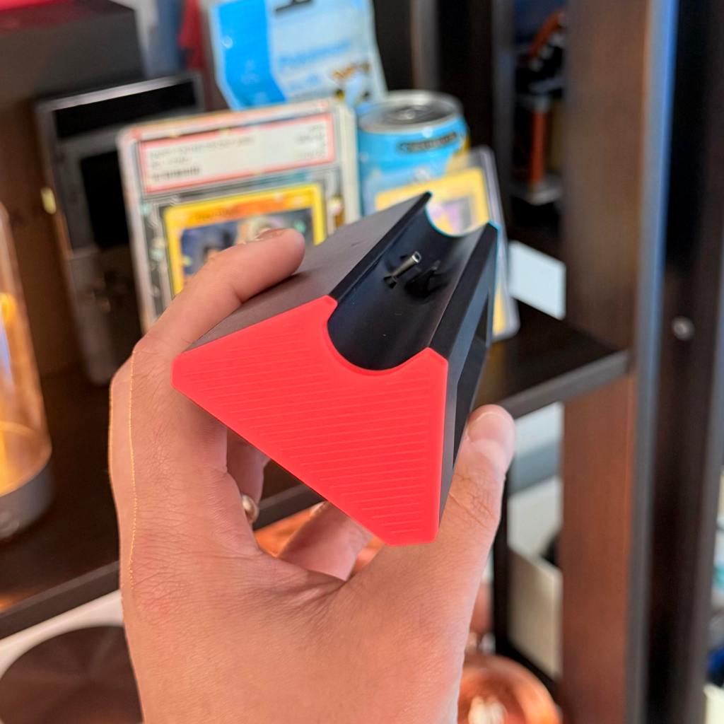 A hand holding a black and red pencil sharpener