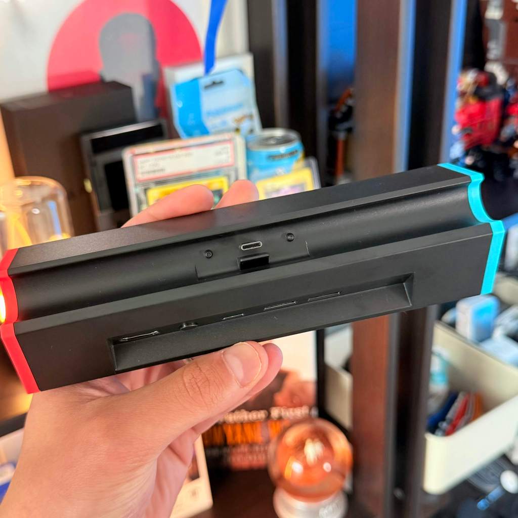 A hand holding a black rectangular object with a red light