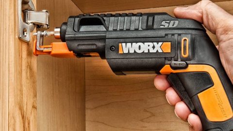 A hand holding a black and orange drill