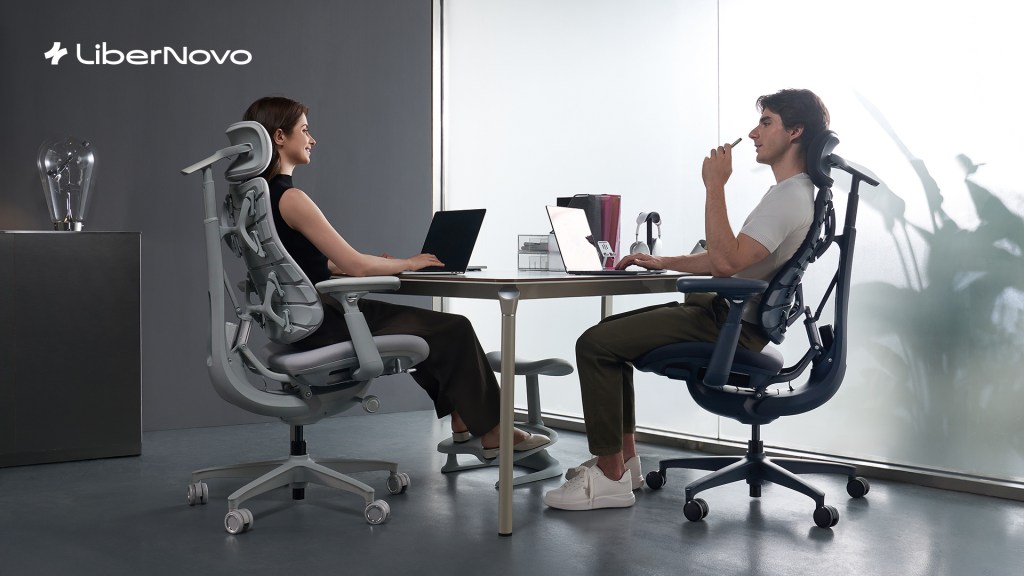 A man and woman sitting at a table with laptops
