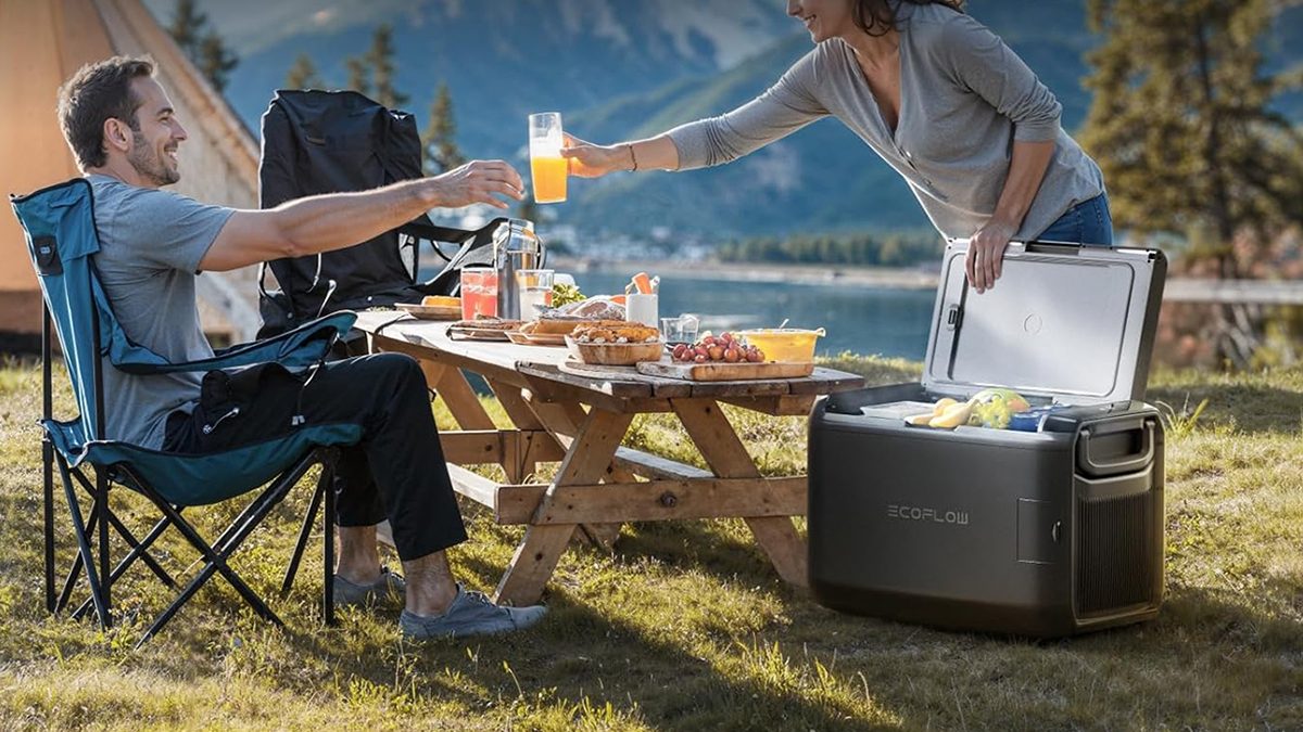 A woman serving a glass of orange juice to a man at a picnic table