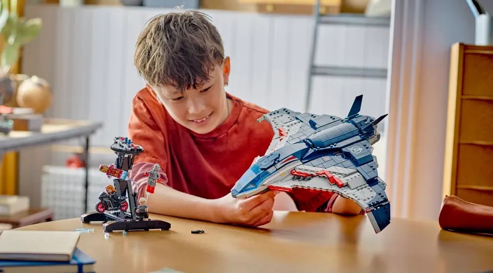 A boy playing with a LEGO Quinjet set