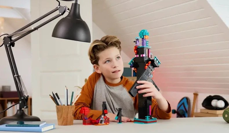 A boy sitting at a table with the LEGO Enderman Tower