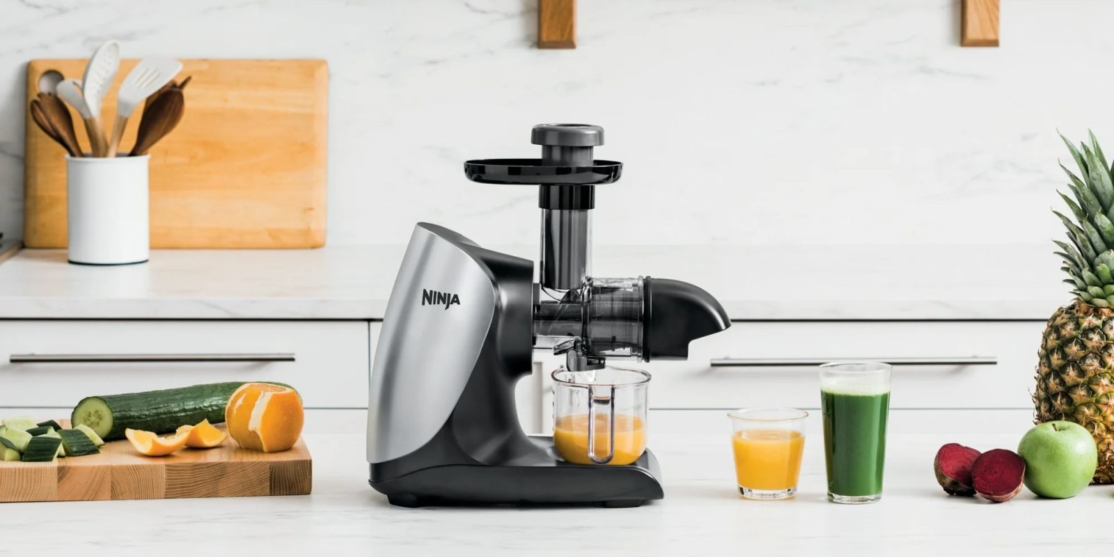A juicer and juice glasses on a counter