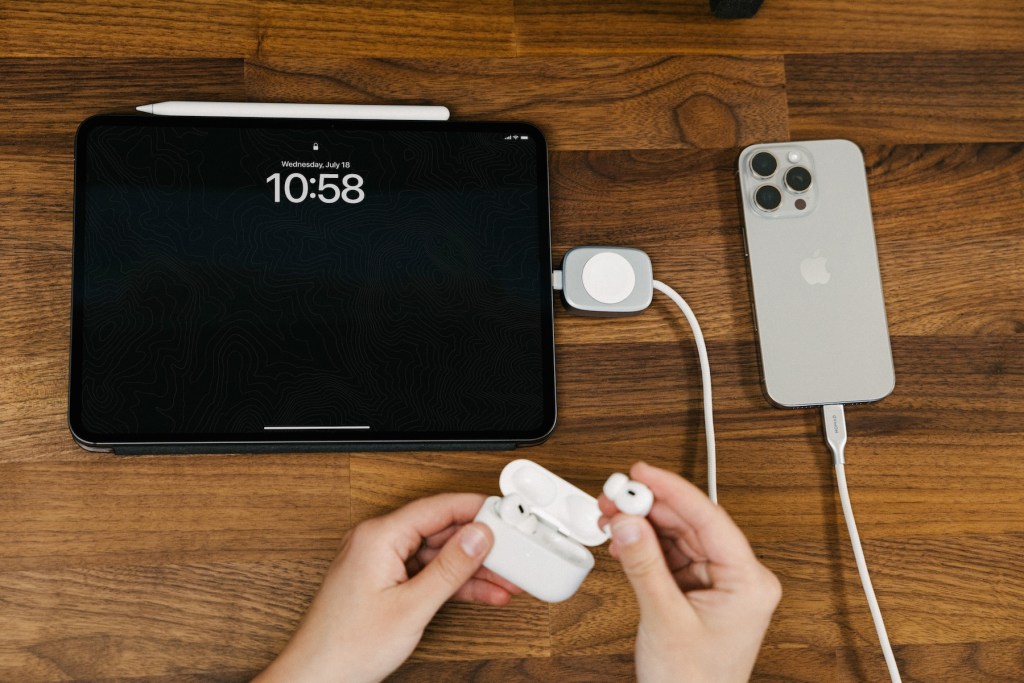 A person holding a white box with a black tablet next to a device
