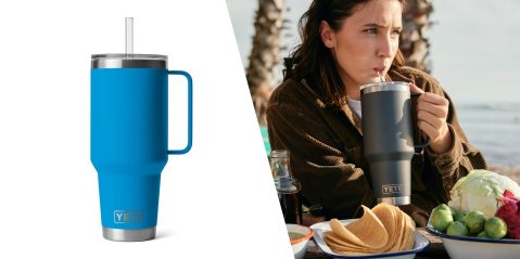 A woman drinking from a blue and black cup