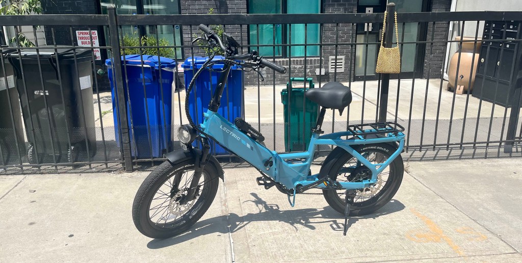 A blue Lectric XP4 750 e-bike parked on a sidewalk