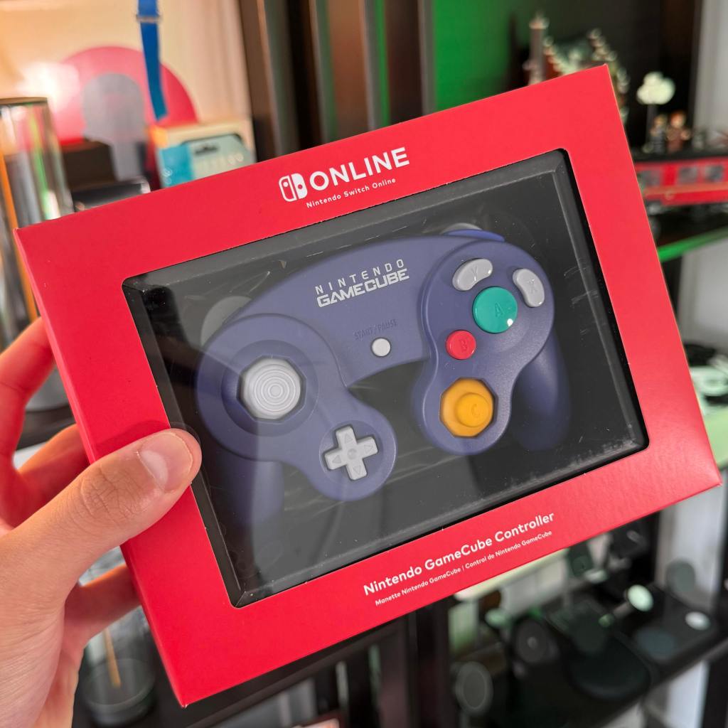 A hand holding a video game controller in a red box
