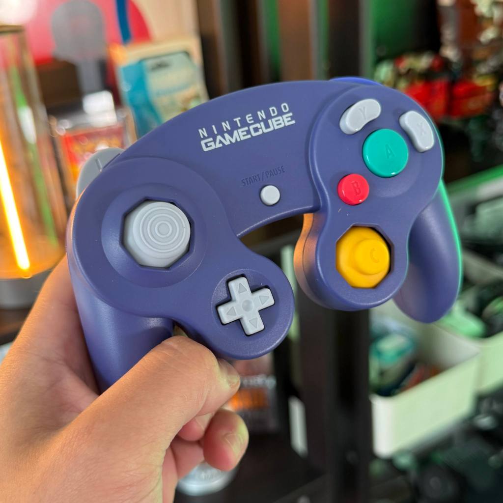 A hand holding a purple video game controller