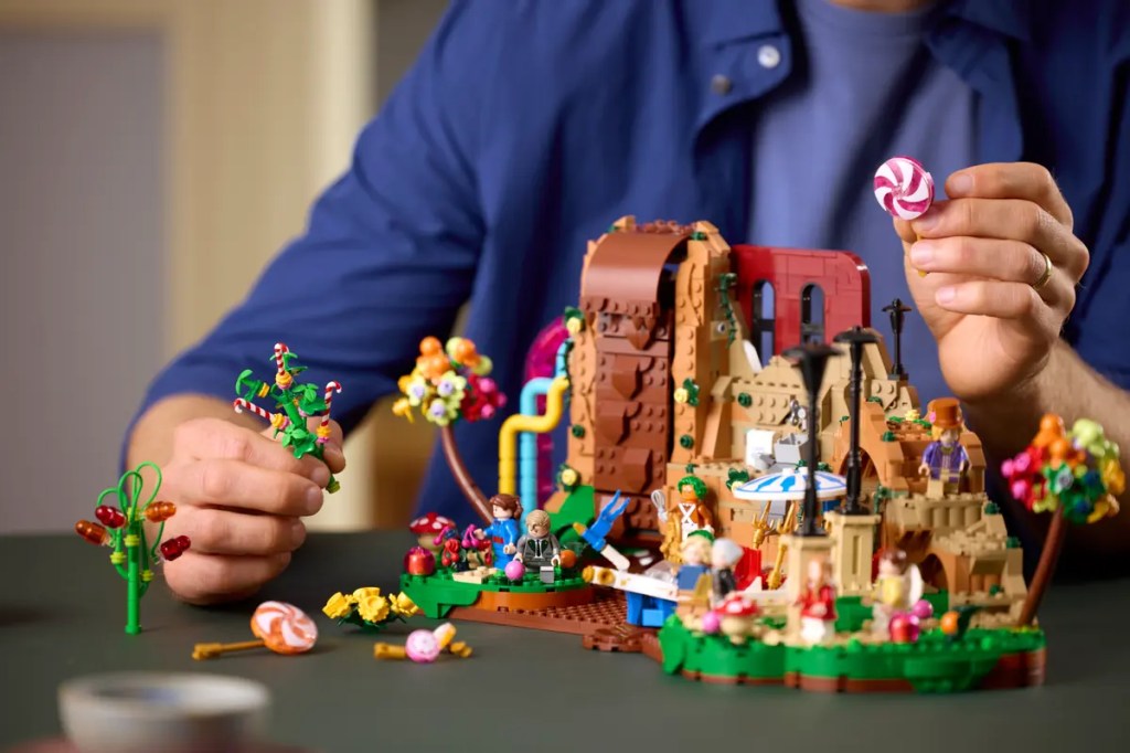 A person holding a candy and a toy as part of LEGO ideas willy wonka set