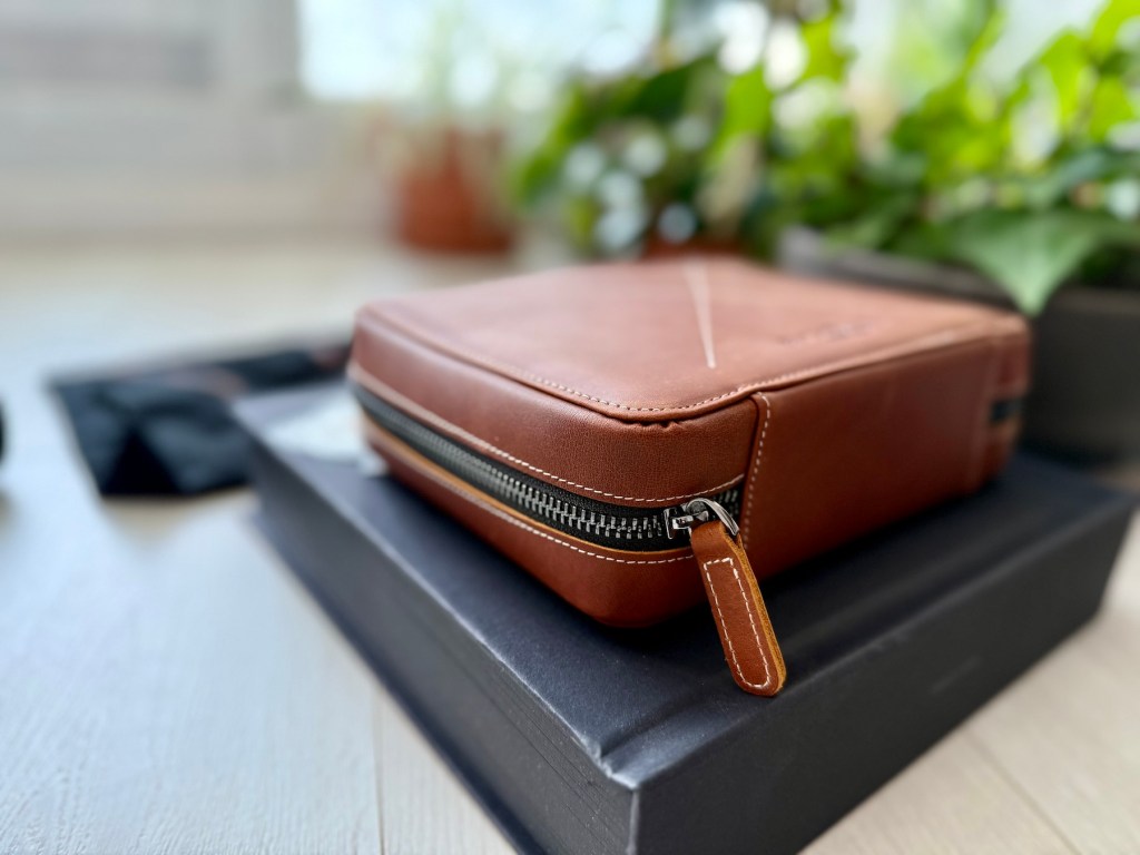 A brown leather case on top of a black book
