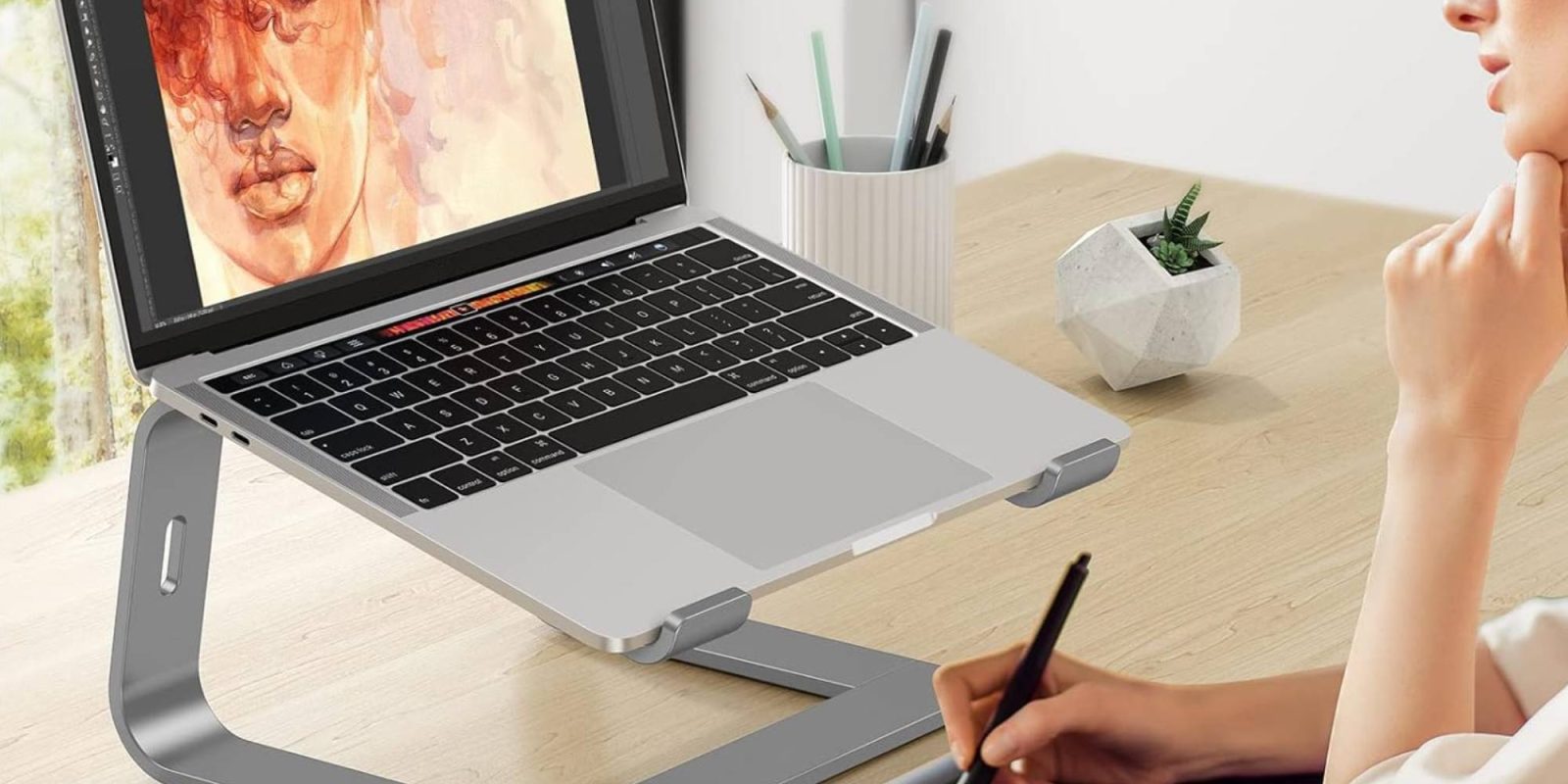 A hand holding a stylus on a laptop
