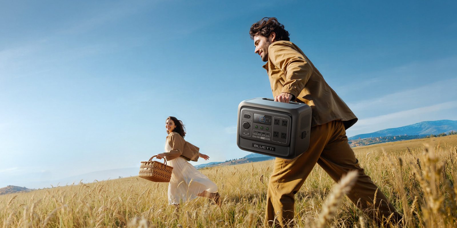 A man and woman running through a field with a radio