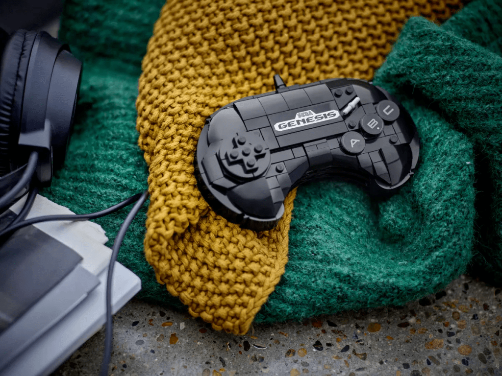 A black video game controller on a yellow knitted blanket