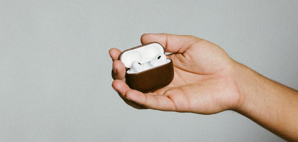 A hand holding a case with white earbuds
