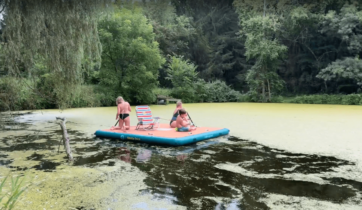 A group of kids on a floating platform in a lake
