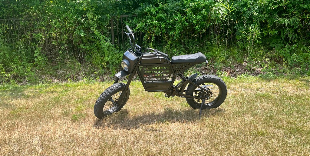 A black Ride1Up Revv1 DRT e-bike parked in a grassy area