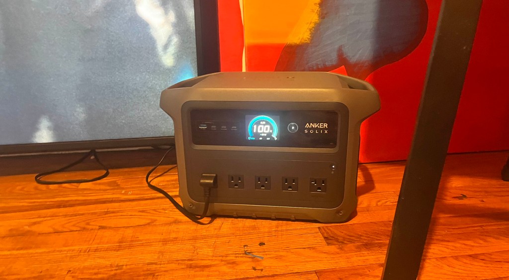 Anker's SOLIX C1000 Gen 2 power supply on a wood floor powering TV