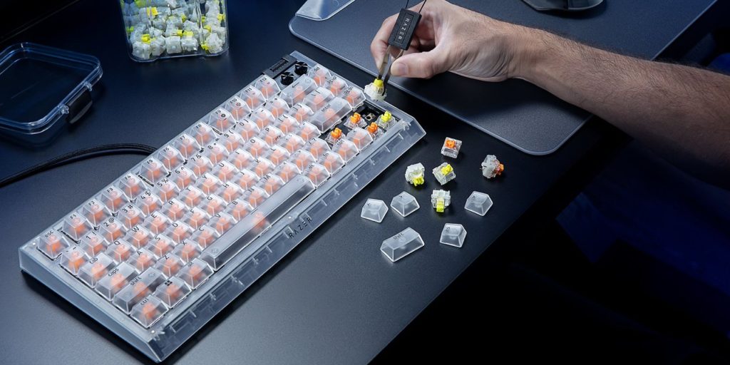 A hand holding a screwdriver to a keyboard