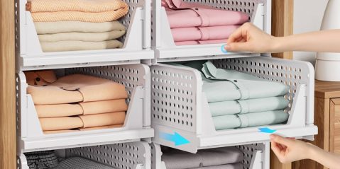A hand picking up a stack of folded clothes