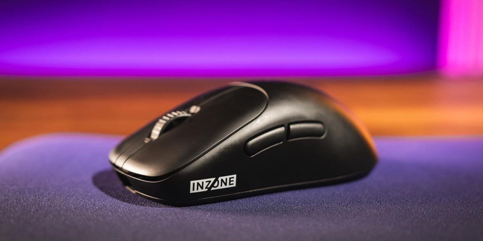 A black computer mouse on a purple and orange surface