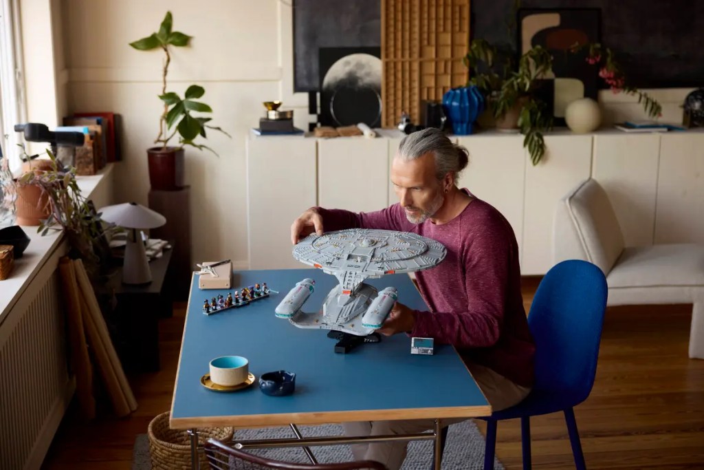 A man sitting at a table with a model of a spaceship