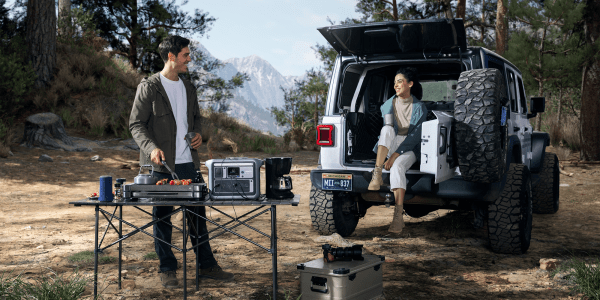 A man and woman cooking food in the back of a car