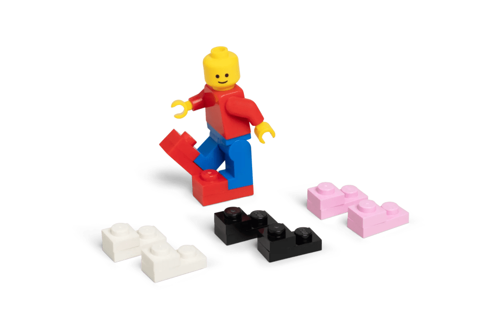 A lego man walking next to several colorful building blocks
