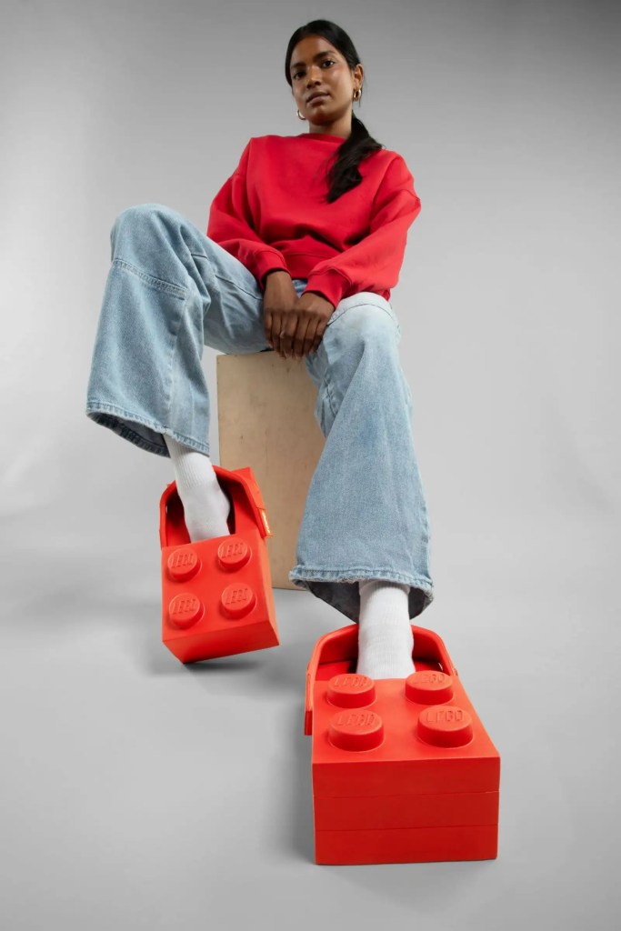 A woman wearing red shirt and jeans sitting on a block shaped platform