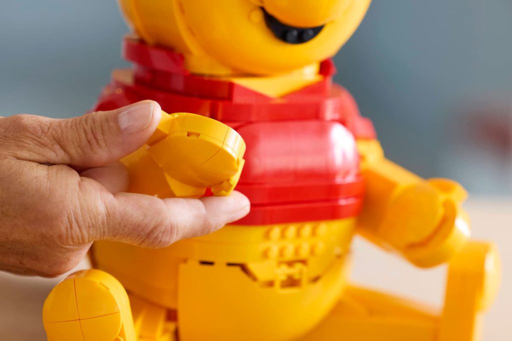 A hand holding LEGO Winnie the Pooh